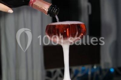 Pièce montée en forme d'anneaux entrelacés avec des figurines de mariés, entourée de bouteilles de champagne.