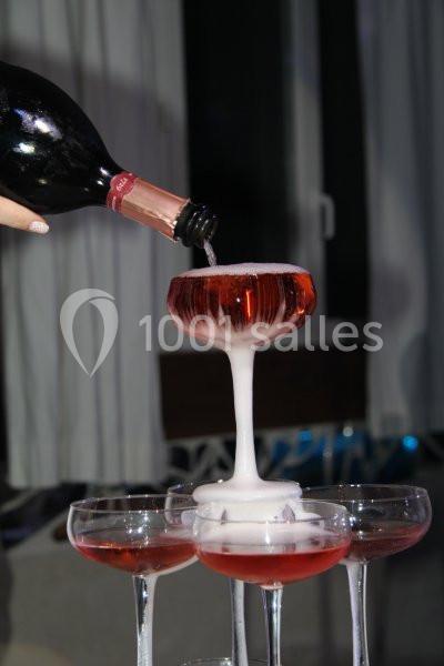 Du vin pétillant rosé est versé dans une coupe, débordant pour remplir d'autres verres en cascade.