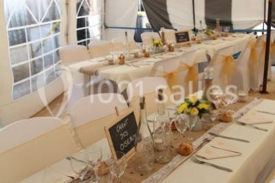 Pièce montée en forme d'anneaux entrelacés avec des figurines de mariés, entourée de bouteilles de champagne.