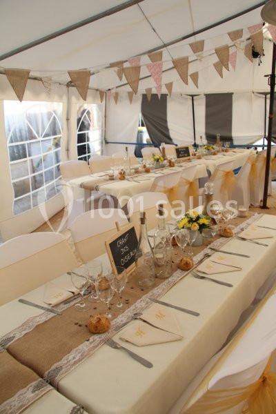 Table décorée pour un événement avec nappes beige et blanche, vaisselle élégante, fleurs et guirlandes en toile de jute.