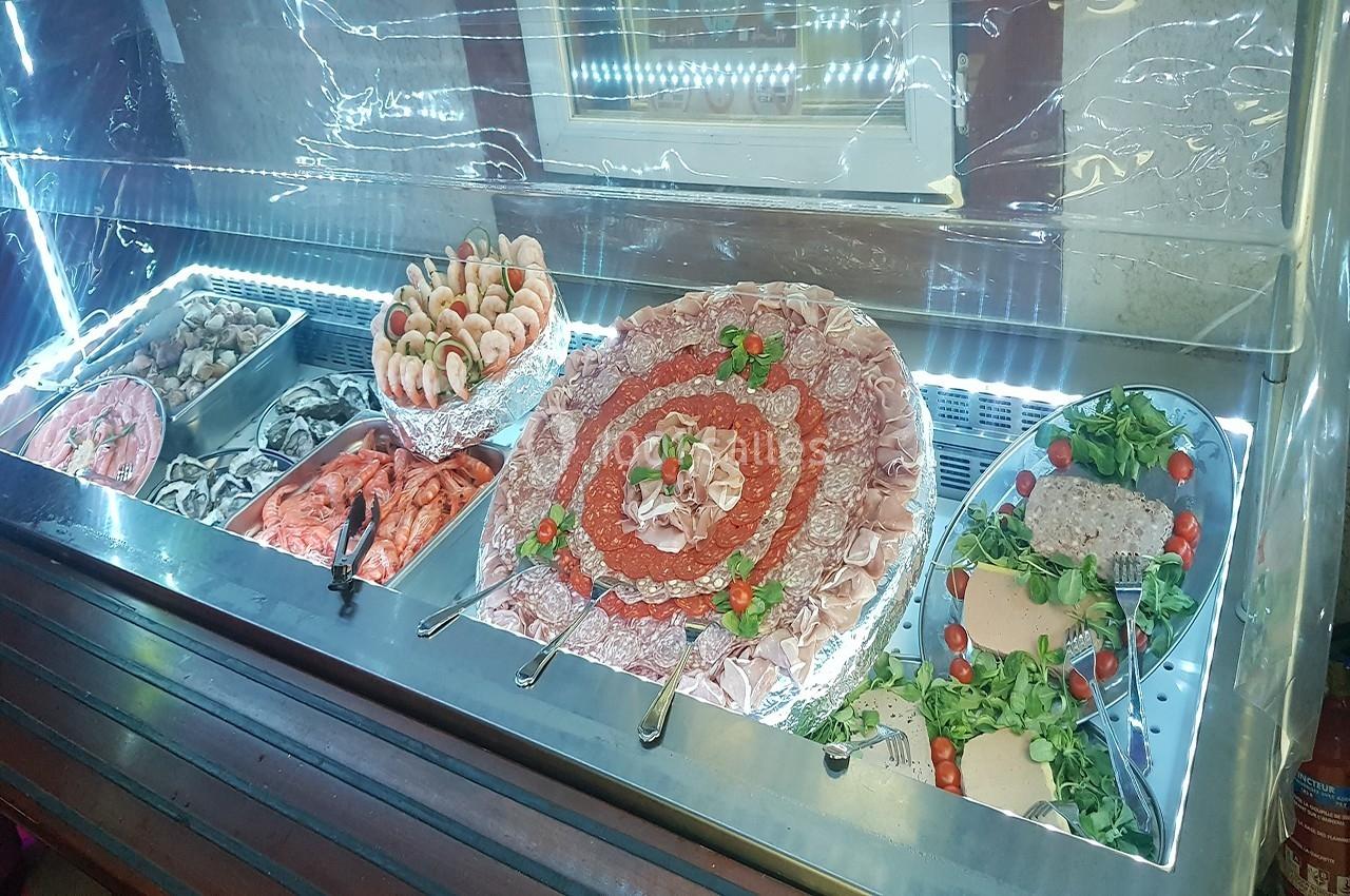 Vitrine réfrigérée présentant un assortiment de charcuteries, fruits de mer et salades garnies.