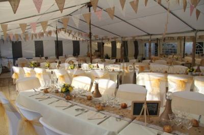 Pièce montée en forme d'anneaux entrelacés avec des figurines de mariés, entourée de bouteilles de champagne.