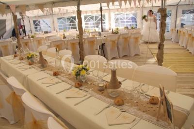 Pièce montée en forme d'anneaux entrelacés avec des figurines de mariés, entourée de bouteilles de champagne.