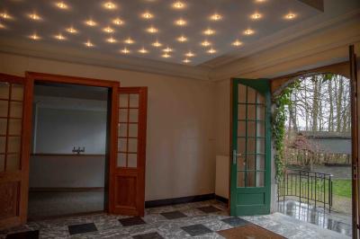 Salle vide avec de grandes baies vitrées donnant sur un espace vert, éclairée par une lumière douce.