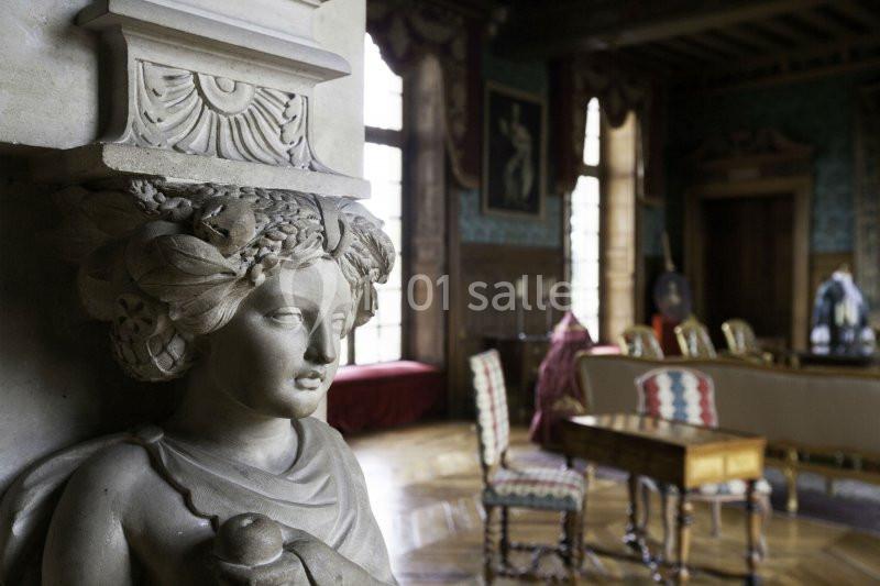 Statue décorative en pierre dans une pièce richement meublée avec des chaises, une table et des fenêtres lumineuses.