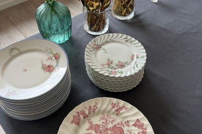 Vue d'une rivière bordée de végétation avec une maison au toit rouge et un ciel partiellement nuageux au coucher du soleil.