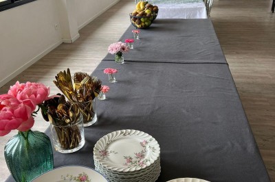 Vue d'une rivière bordée de végétation avec une maison au toit rouge et un ciel partiellement nuageux au coucher du soleil.