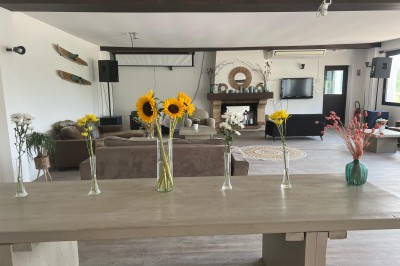 Vue d'une rivière bordée de végétation avec une maison au toit rouge et un ciel partiellement nuageux au coucher du soleil.