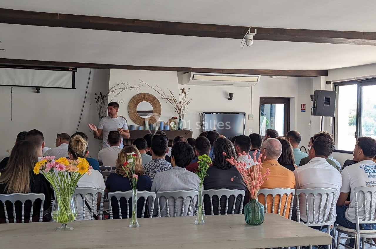 Un groupe de personnes assises dans une salle, écoutant un intervenant debout devant un écran.