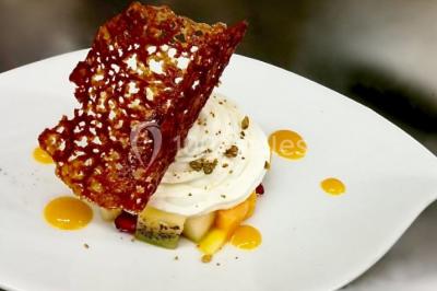 Salon d'hôtel avec canapés beiges, table basse, bureau, chaise noire et grande baie vitrée donnant sur un jardin.