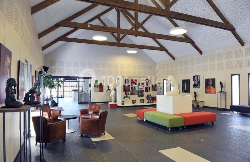 Salle d'exposition lumineuse avec sculptures, peintures colorées sur les murs et mobilier moderne.