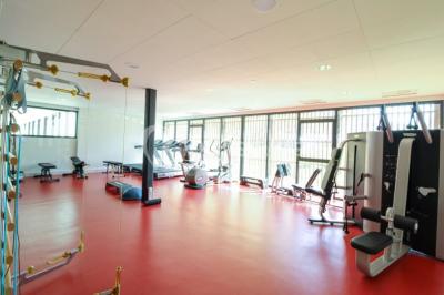 Salon d'hôtel avec canapés beiges, table basse, bureau, chaise noire et grande baie vitrée donnant sur un jardin.