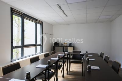 Salle de conférence moderne avec rangées de sièges en bois et éclairage suspendu.