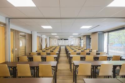 Salle de conférence moderne avec rangées de sièges en bois et éclairage suspendu.