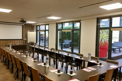 Salle de conférence moderne avec rangées de sièges en bois et éclairage suspendu.