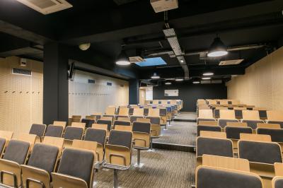Salle de conférence moderne avec rangées de sièges en bois et éclairage suspendu.