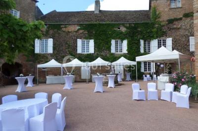Vue aérienne d'un village avec un étang, des champs, des arbres et des collines à l'horizon.