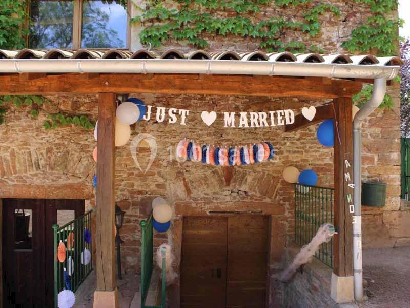 Décoration de mariage avec une bannière ’Just Married’, des ballons et des guirlandes colorées sur une façade en pierre.