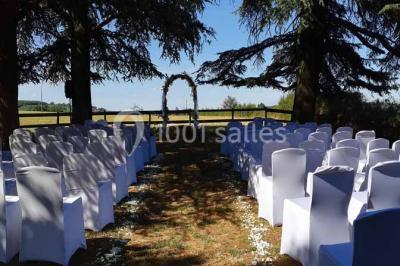 Vue aérienne d'un village avec un étang, des champs, des arbres et des collines à l'horizon.