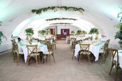 Chambre lumineuse avec lit double, poutres apparentes, parquet en bois, miroir doré et bureau ancien.