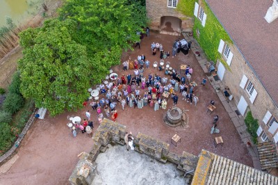 Chambre lumineuse avec lit double, poutres apparentes, parquet en bois, miroir doré et bureau ancien.