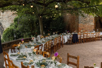 Chambre lumineuse avec lit double, poutres apparentes, parquet en bois, miroir doré et bureau ancien.