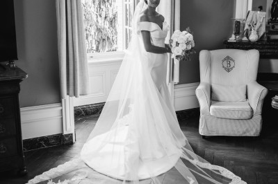 Chambre lumineuse avec lit double, poutres apparentes, parquet en bois, miroir doré et bureau ancien.