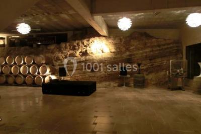 Bouteilles de vin blanc ’Hauts de L'Évêque 2018’ exposées sur un présentoir en bois dans une cave à vin.