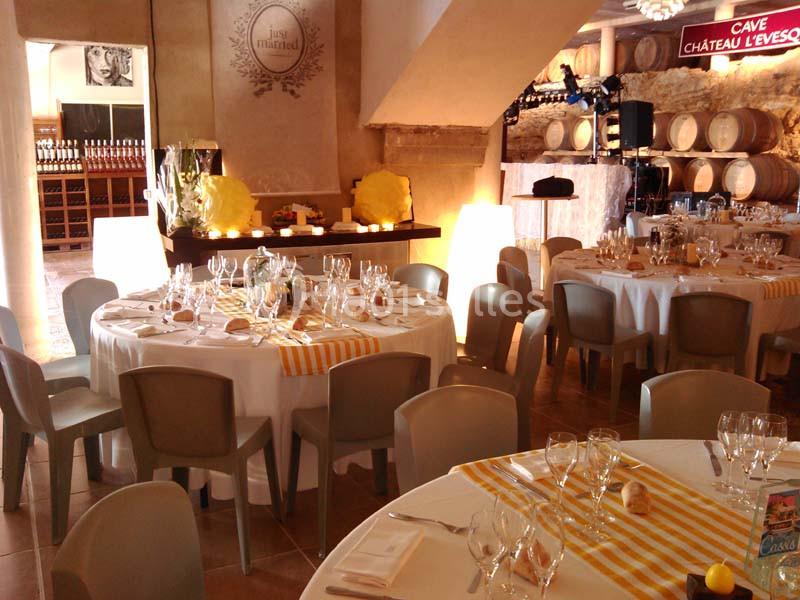 Salle de réception décorée avec des tables rondes dressées, nappes blanches et chemins de table jaunes, ambiance chaleureuse.
