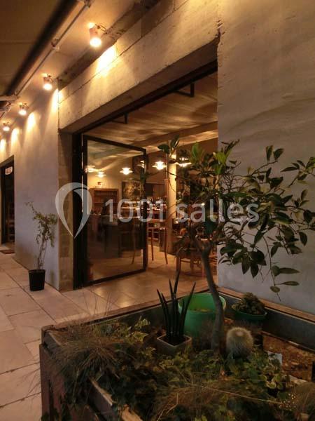 Entrée d'un restaurant avec une grande baie vitrée, éclairage chaleureux et plantes en premier plan.