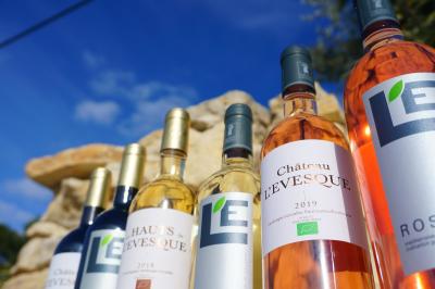 Bouteilles de vin blanc ’Hauts de L'Évêque 2018’ exposées sur un présentoir en bois dans une cave à vin.