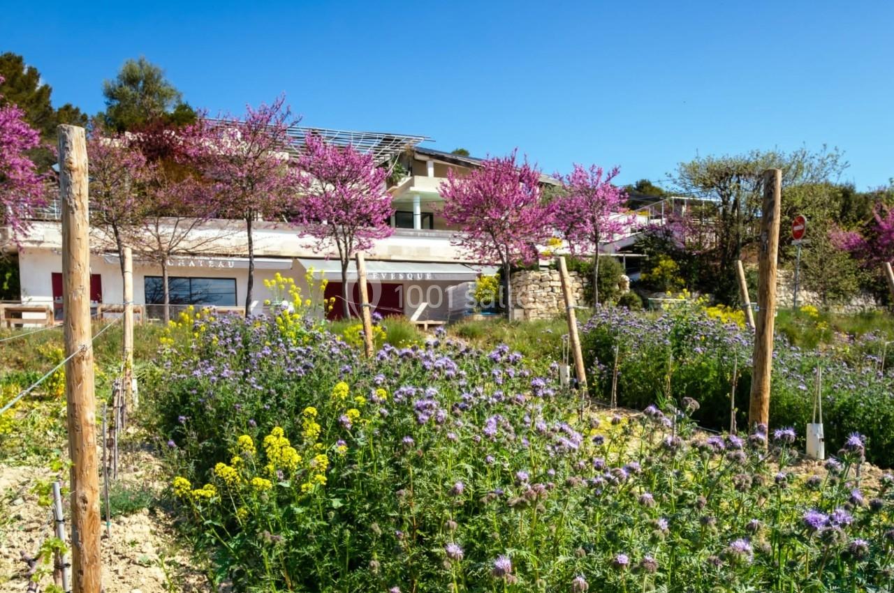 Champ fleuri avec des fleurs violettes et jaunes devant un bâtiment moderne entouré d'arbres en fleurs.