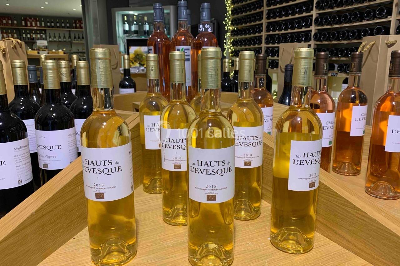 Bouteilles de vin blanc ’Hauts de L'Évêque 2018’ exposées sur un présentoir en bois dans une cave à vin.