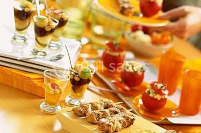 Groupe de personnes discutant sur une terrasse extérieure, entourée de fleurs et de mobilier de jardin.