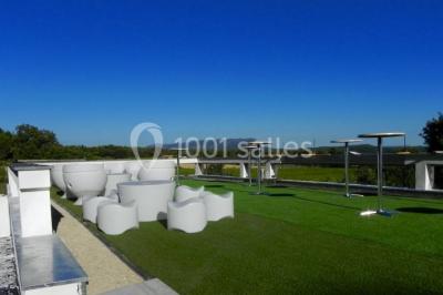 Groupe de personnes discutant sur une terrasse extérieure, entourée de fleurs et de mobilier de jardin.