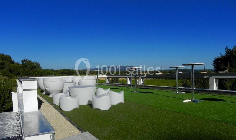 Terrasse extérieure avec mobilier moderne sur gazon synthétique, offrant une vue dégagée sur un paysage naturel.