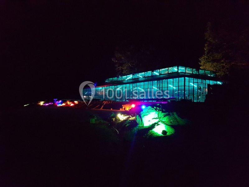 Serre illuminée par des lumières colorées dans un environnement nocturne.