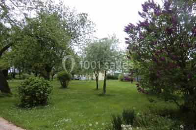 Table élégamment dressée avec nappes blanches, bougies, fleurs, verres et petits pains alignés.