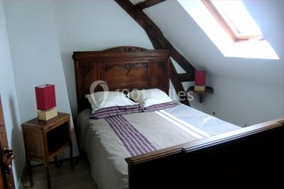 Table élégamment dressée avec nappes blanches, bougies, fleurs, verres et petits pains alignés.