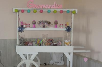 Table élégamment dressée avec nappes blanches, bougies, fleurs, verres et petits pains alignés.