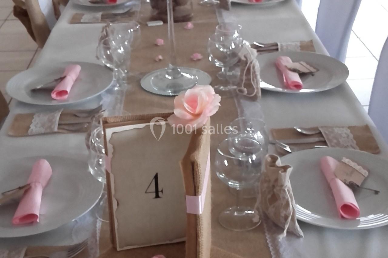 Table de réception décorée avec des nappes en toile de jute, des fleurs, des serviettes roses et un centre de table floral.