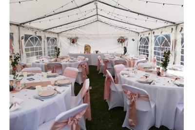 Table élégamment dressée avec nappes blanches, bougies, fleurs, verres et petits pains alignés.