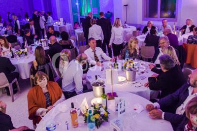 Piscine extérieure entourée de tables hautes, chaises colorées et structures gonflables, avec colline en arrière-plan.