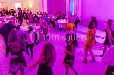 Piscine extérieure entourée de tables hautes, chaises colorées et structures gonflables, avec colline en arrière-plan.