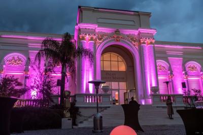 Piscine extérieure entourée de tables hautes, chaises colorées et structures gonflables, avec colline en arrière-plan.