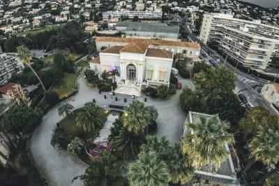 Piscine extérieure entourée de tables hautes, chaises colorées et structures gonflables, avec colline en arrière-plan.