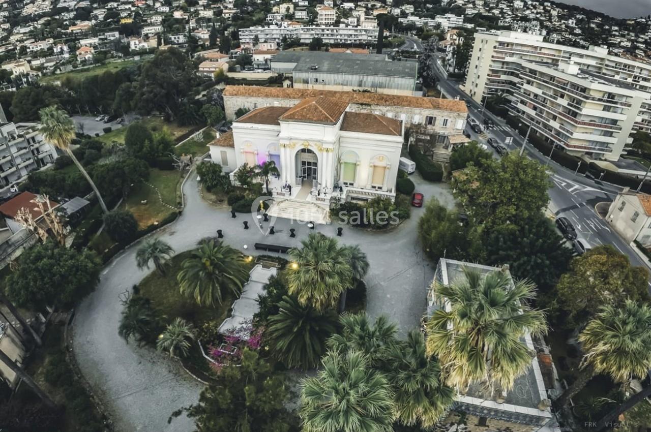Vue aérienne d'un bâtiment historique entouré de jardins, situé dans un quartier résidentiel avec des immeubles en arrière…