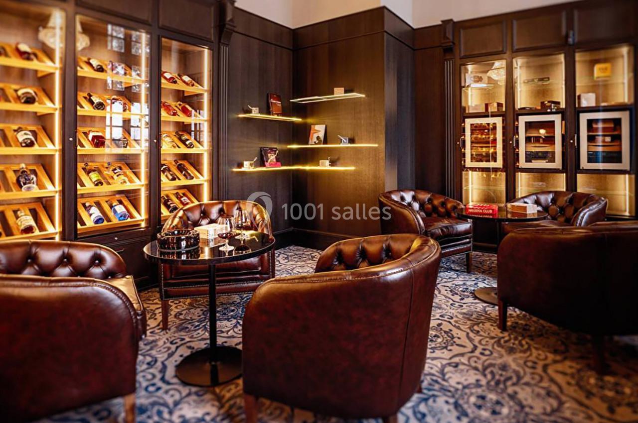 Salle élégante avec fauteuils en cuir, vitrines éclairées contenant des cigares et ambiance chaleureuse.