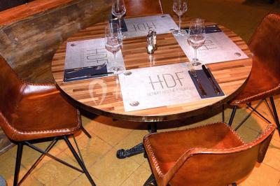 Salle sombre avec éclairage violet, plafond métallique, tables et chaises dispersées sur un sol à carreaux.