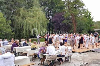 Salle sombre avec éclairage violet, plafond métallique, tables et chaises dispersées sur un sol à carreaux.